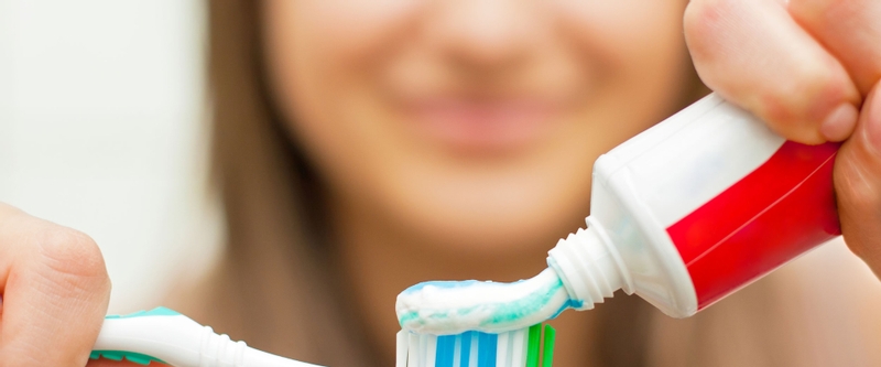 Woman applying toothpaste to her brush